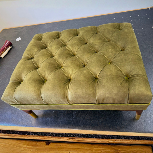 Luxe capitonné ottoman met olijfgroene stoffering en houten poten. Stijlvolle voetenbank met tijdloze uitstraling en hoog comfort.